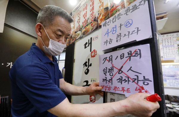 서울을 비롯한 수도권에 대한 사회적 거리두기 개편안 시행이 일주일 연기된 1일 오후 서울 시내 한 식당에서 사장님 '7월 1일부터 6인까지 식사 가능'이라고 적힌 안내문에 'X' 표시를 하고 있다. (사진=뉴스핌 제공)